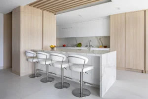 High-rise penthouse kitchen by Sarah Z Designs featuring natural millwork, warm architectural light and refined materials that embody biophilic living in Miami.