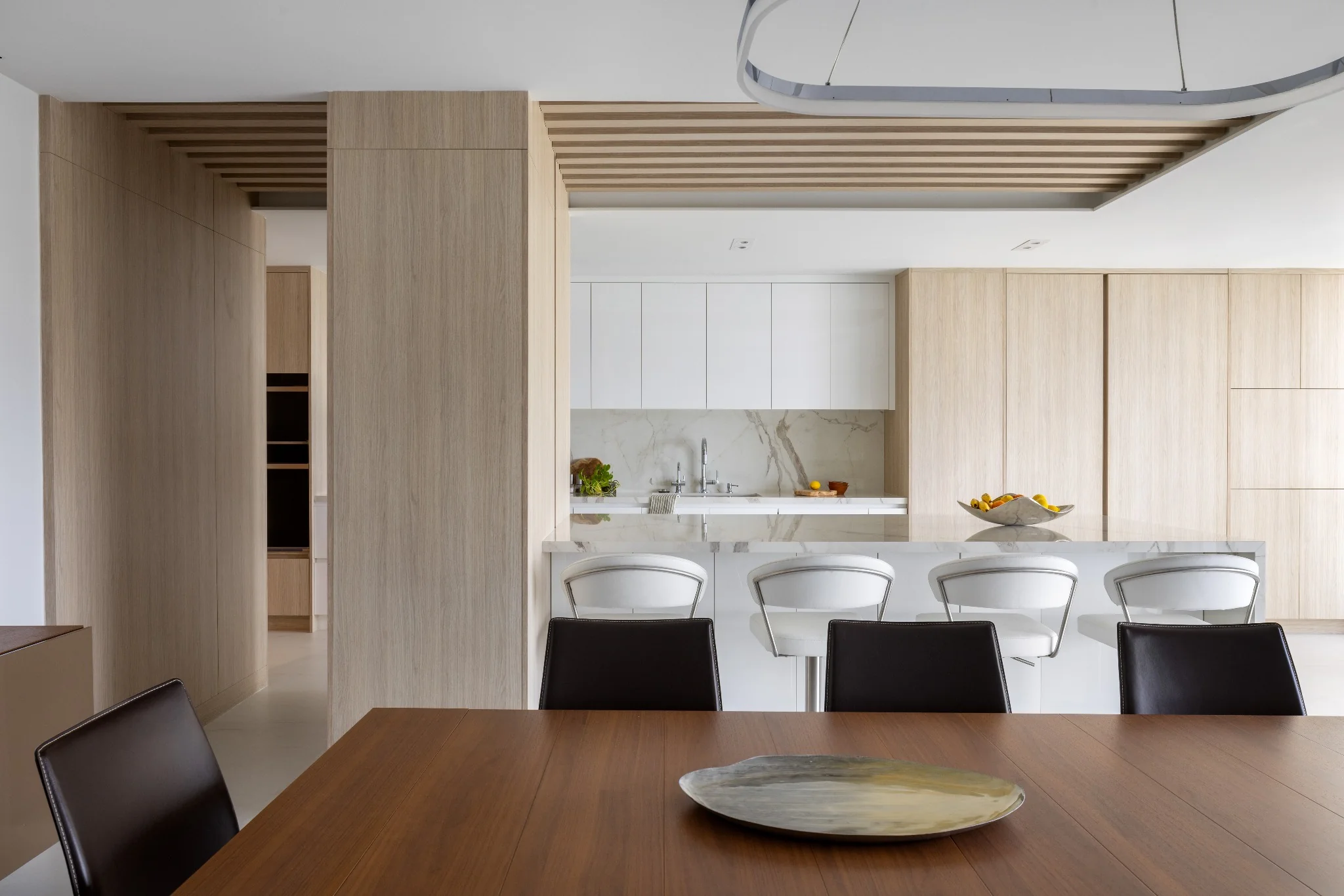 Open-plan Brickell penthouse living space by Sarah Z Designs where custom millwork, natural stone and architectural rhythm work as one biophilic system to soften the urban skyline.