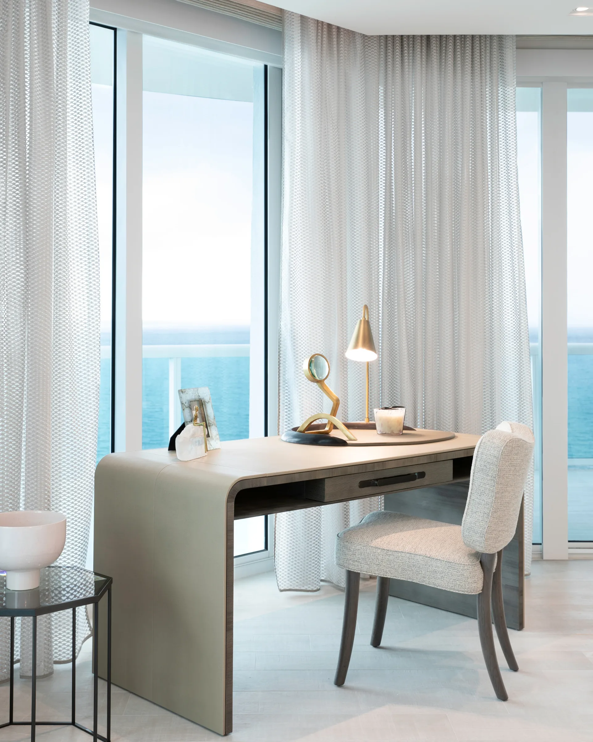 Window-side workspace with unobstructed Atlantic views, layered natural linens and warm brass accents