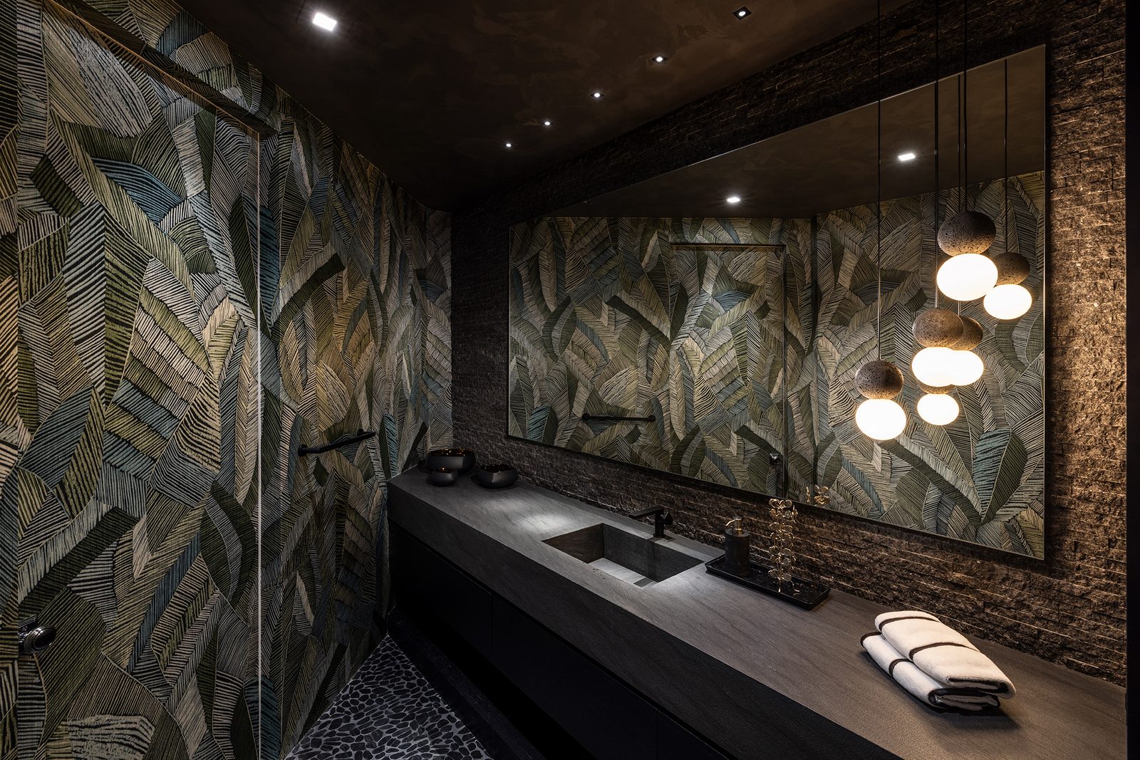 A dim powder room lined in a botanical wallcovering works as a pocket of refuge.