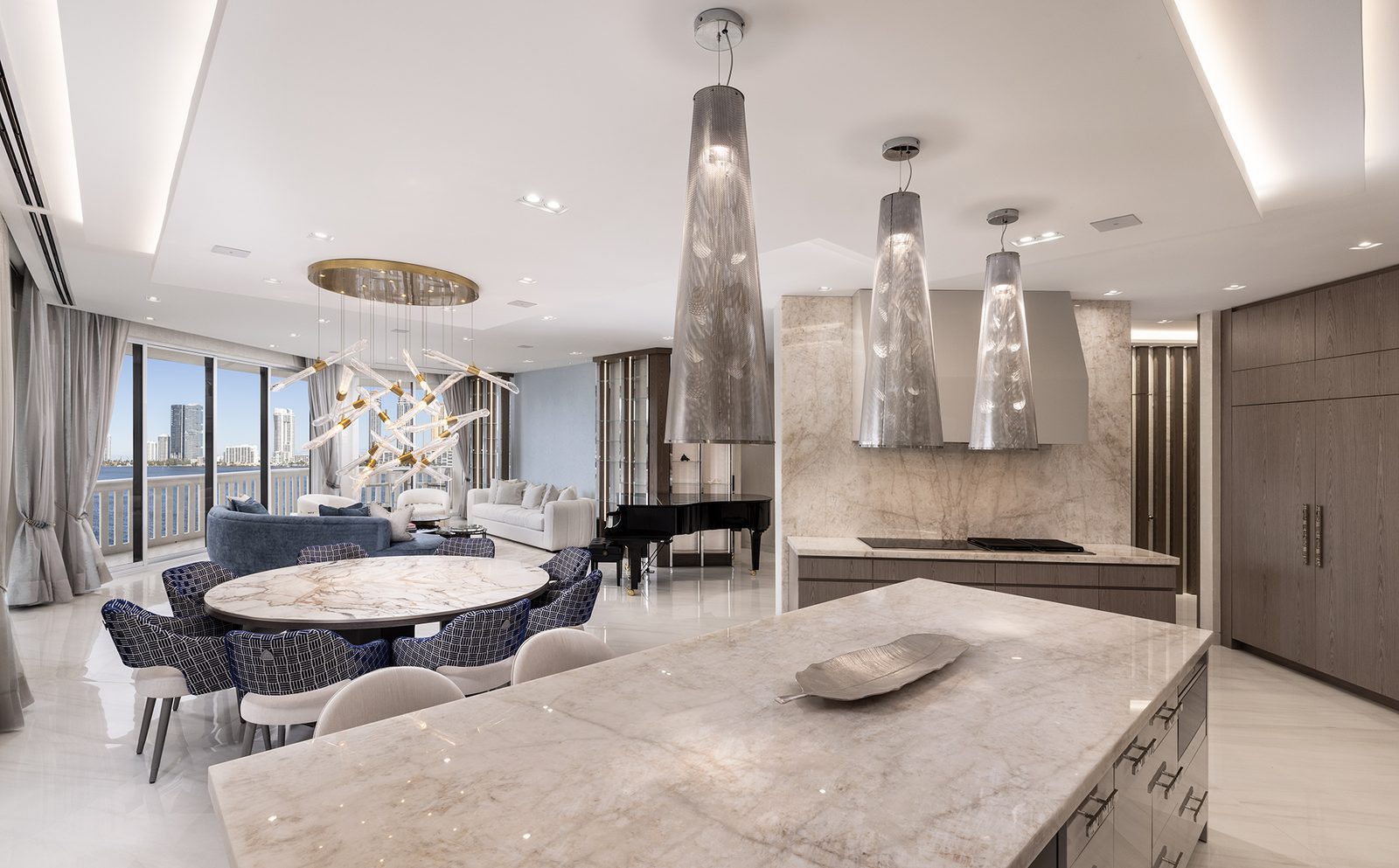 The great room opens from the kitchen island across dining and living to the water beyond.