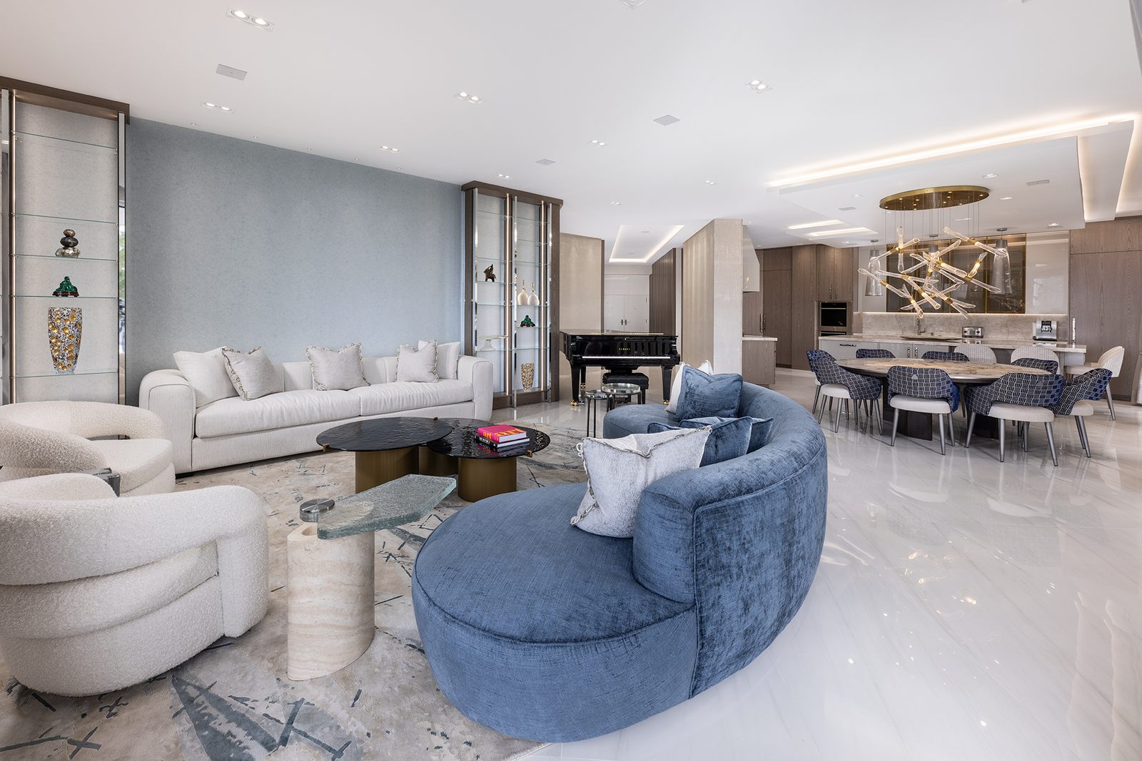 A curved velvet sofa, round tables and a sculptural chandelier soften the geometry of the plan.