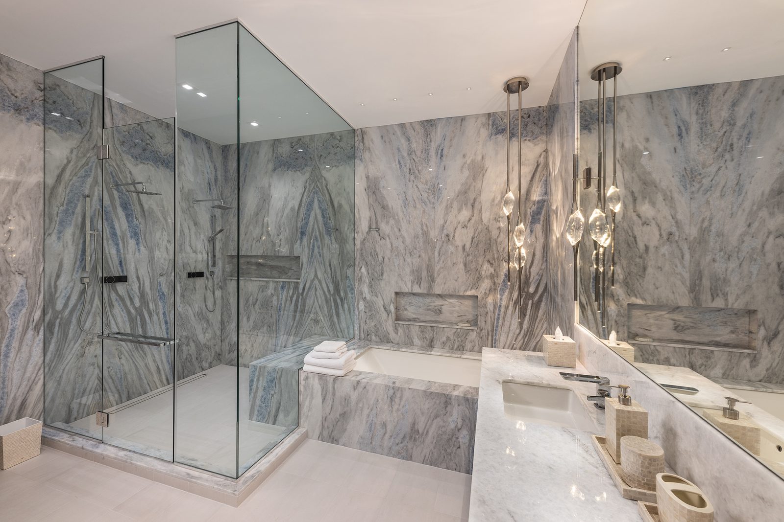 Bookmatched marble wraps the shower and tub: intricate in pattern, ordered in its symmetry.